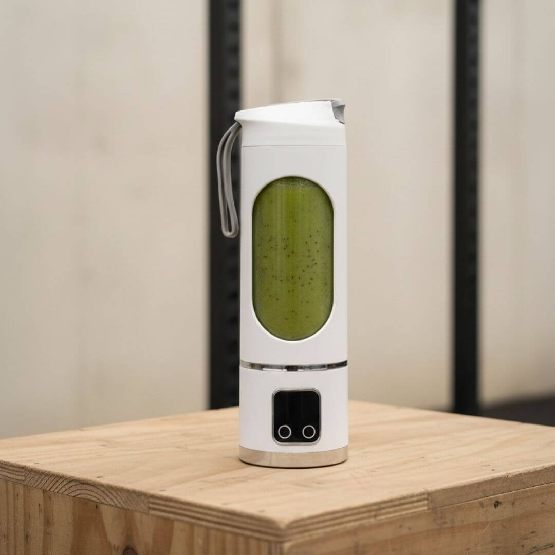 Mixeur portable Mixtoo blanc avec smoothie vert détox, posé sur une boxe en bois dans une salle de sport pour une collation saine après l'entraînement.